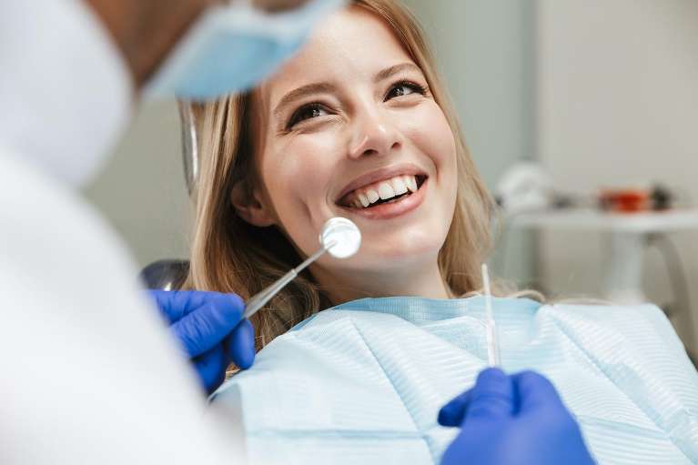 blonde woman sitting in dental exam chair | veneers mt pleasant sc