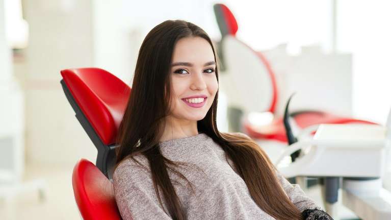 Lady with front dental crown on a red dental chair in Mt Pleasant