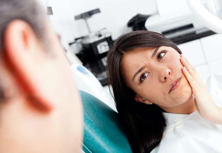woman holding jaw from TMJ pain
