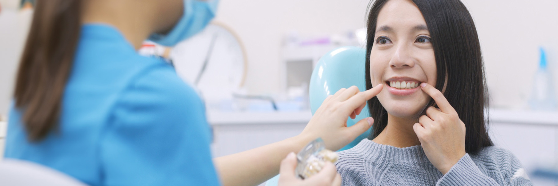 Smiling woman pointing to her teeth during a cosmetic dentistry consultation with her dentist