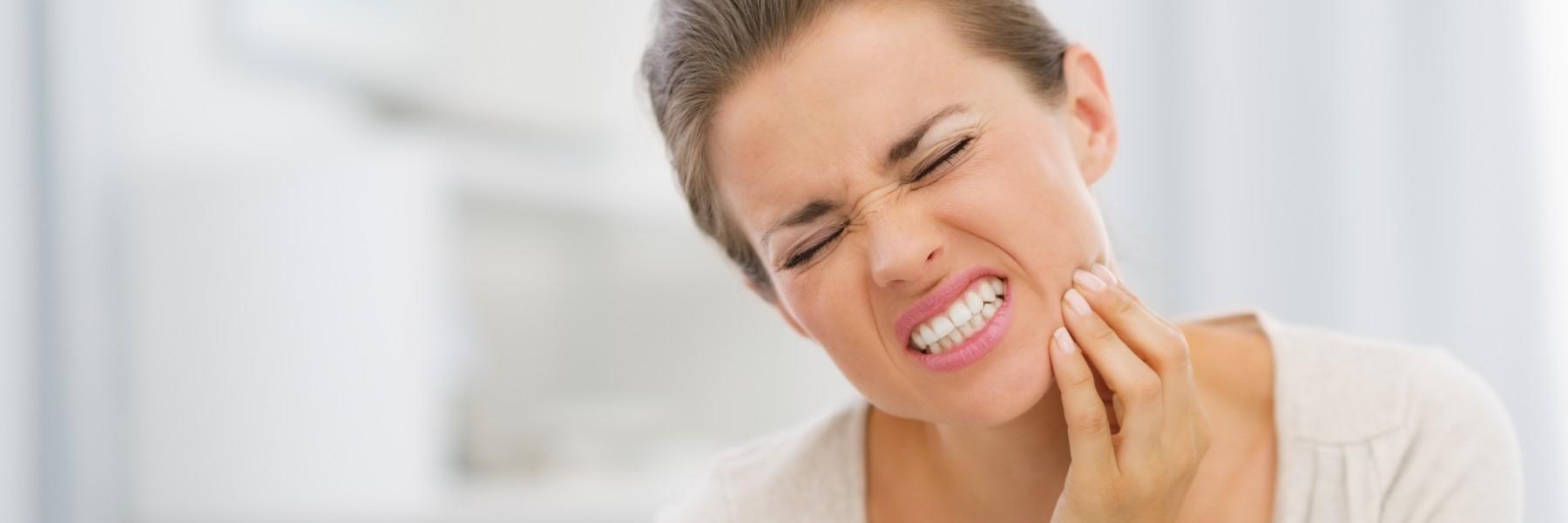 Woman holding face in pain from teeth grinding and TMJ